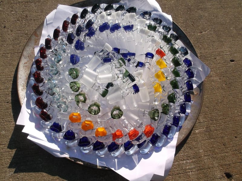 A tray of hand-made glass beads arranged in rings of blue, green, red and orange