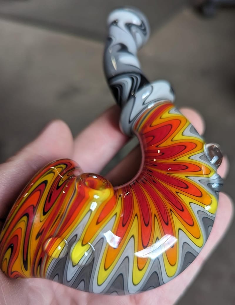 A fan-worked glass piece in red and orange held in one hand