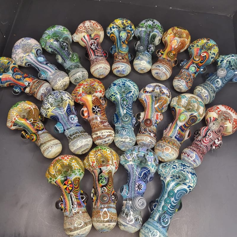 Around forty hand-blown glass spoon pipes laid out in a fan, each one a different colour and pattern