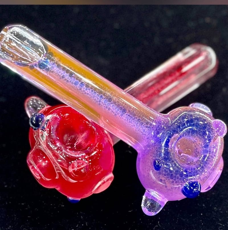 A pink and a purple hand pipe with raised dot work and glitter frit