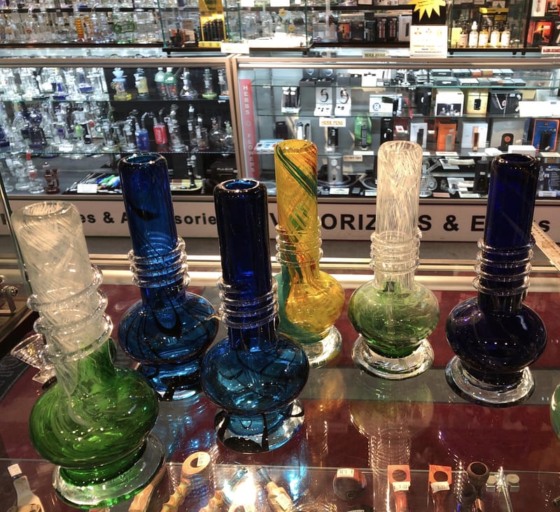 A row of coloured glass water pipes in the display case at Dryden Dispensary's smoke shop