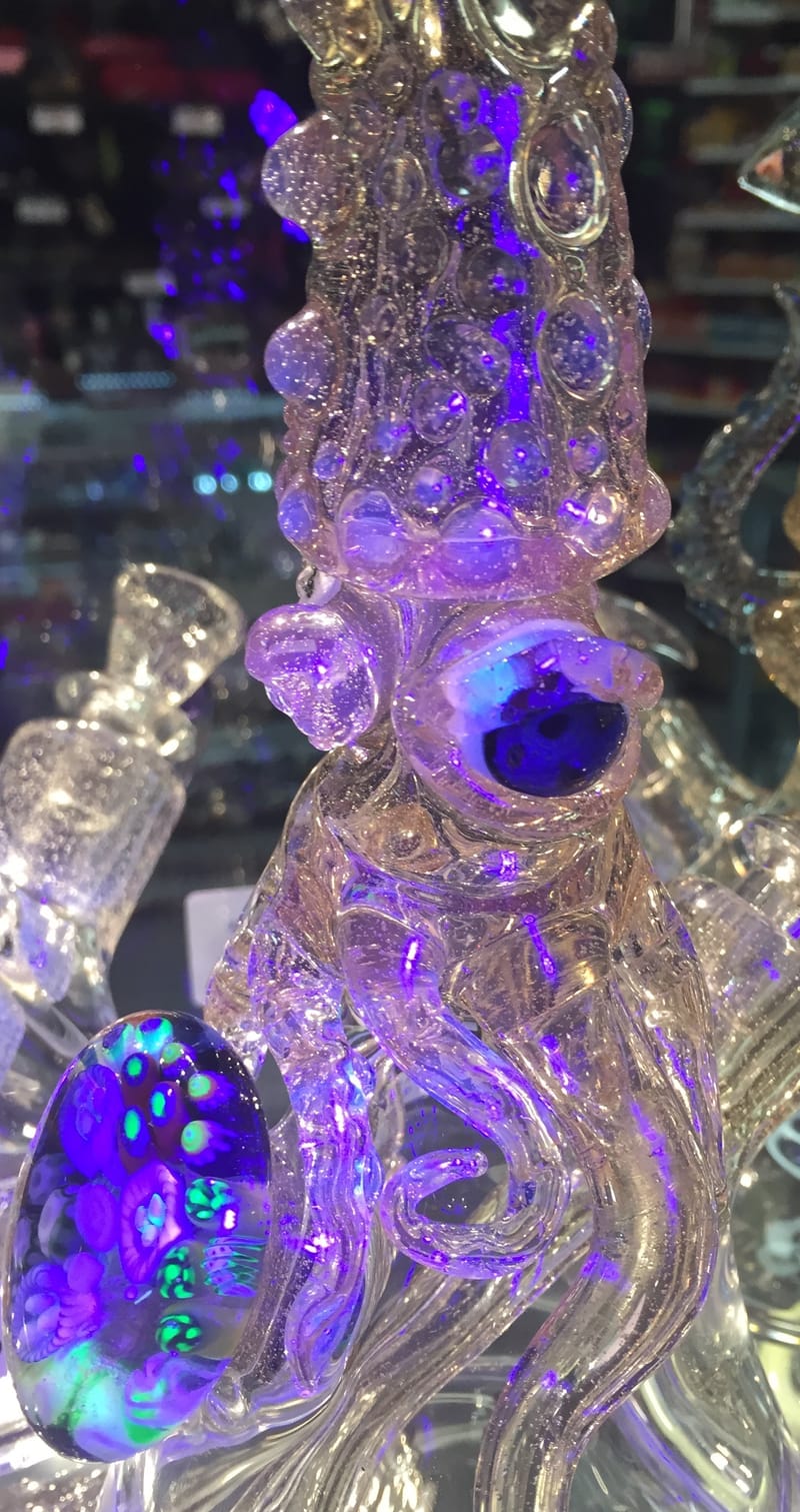A clear sculpted water pipe with purple accents, lit from behind