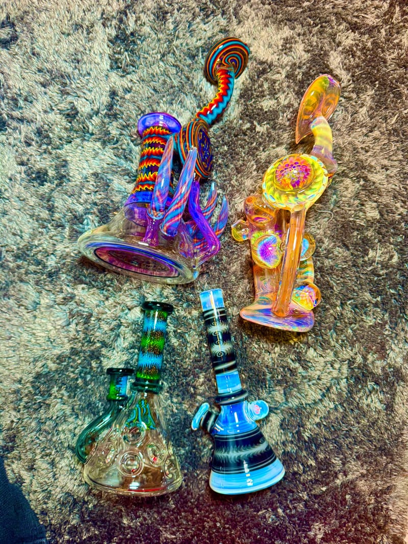 Two brightly worked water pipes in rainbow colours, photographed on stone