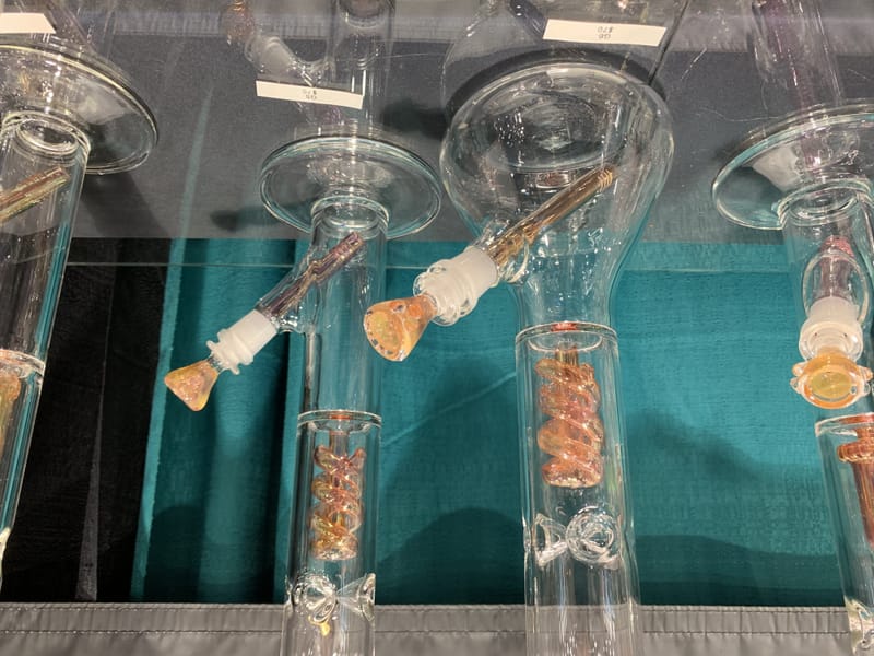 Clear straight-tube water pipes with amber twist work, against a teal backdrop